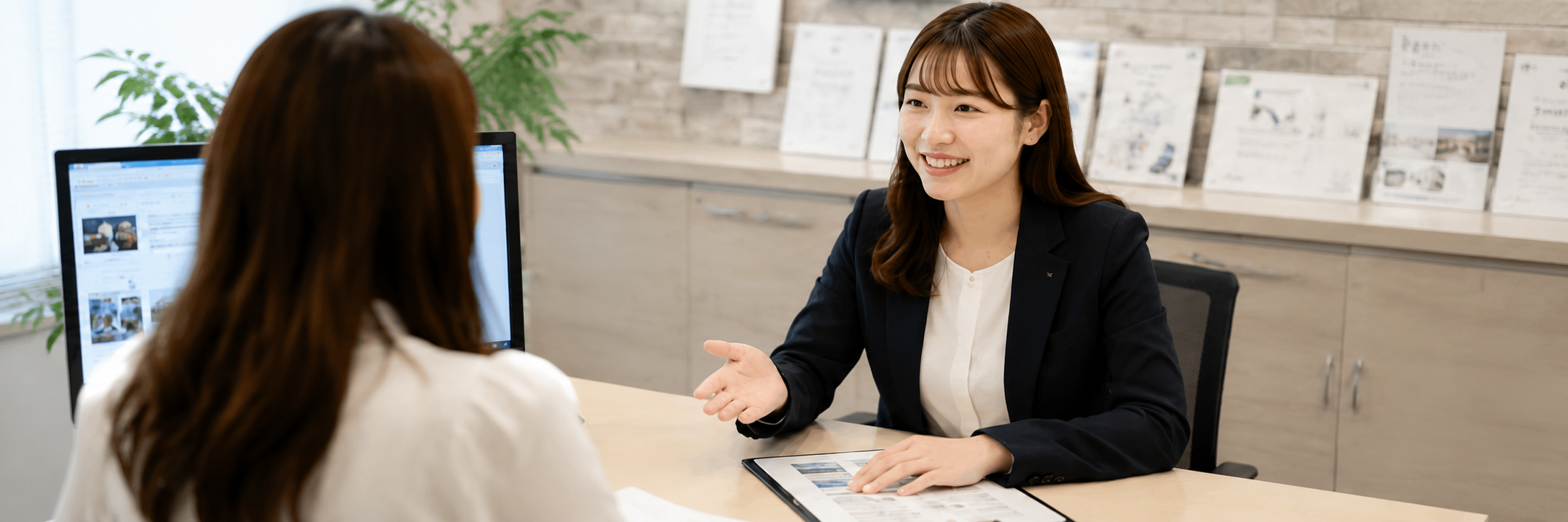 不動産会社の女性スタッフがお客様へ住まいを案内している様子